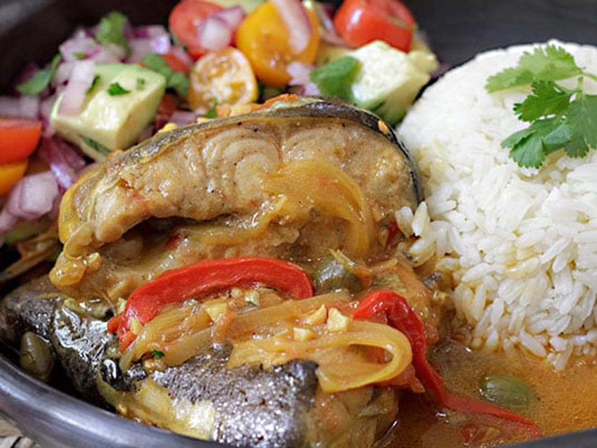 Filete de bagre guisado en salsa de tomate y pimentón, servido con arroz blanco y ensalada