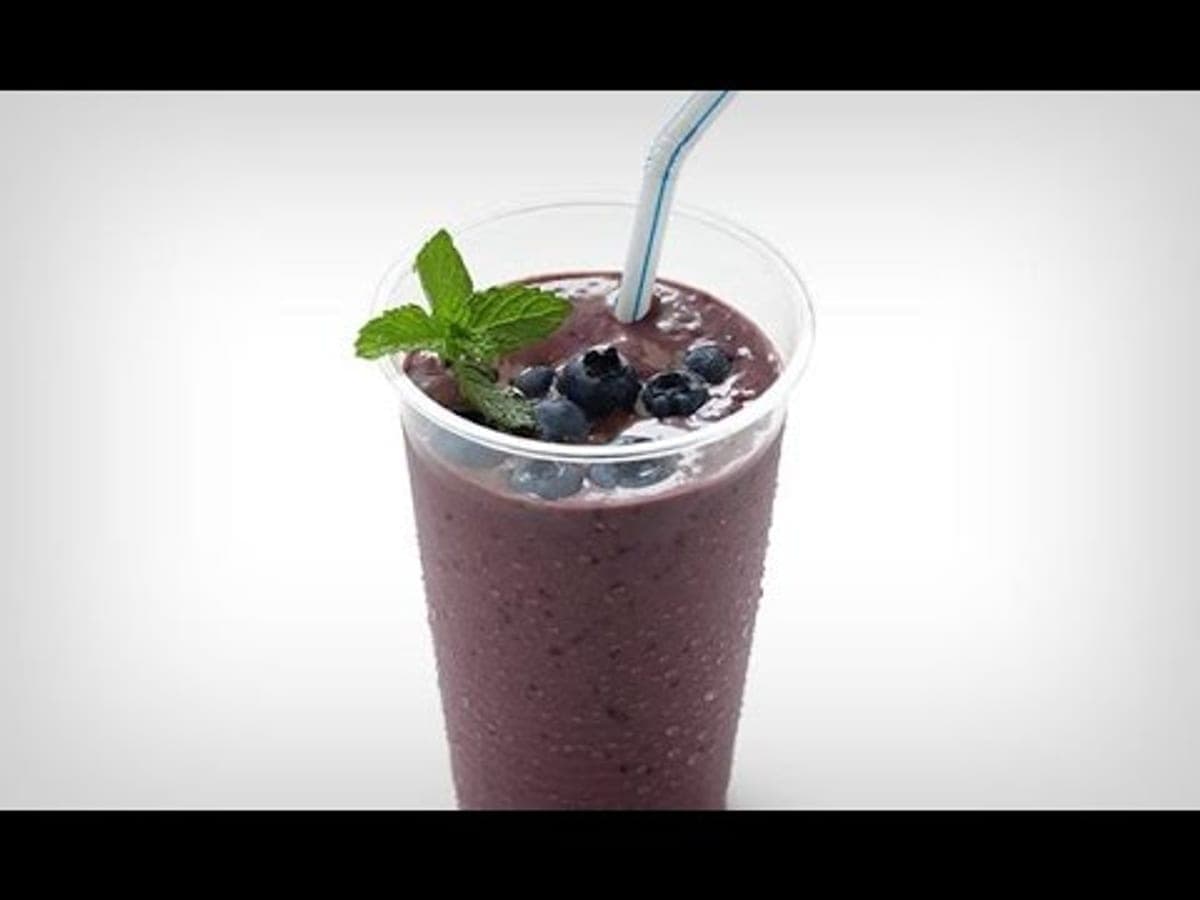 Jugo de macana morado servido en un vaso, decorado con arándanos y hierbabuena