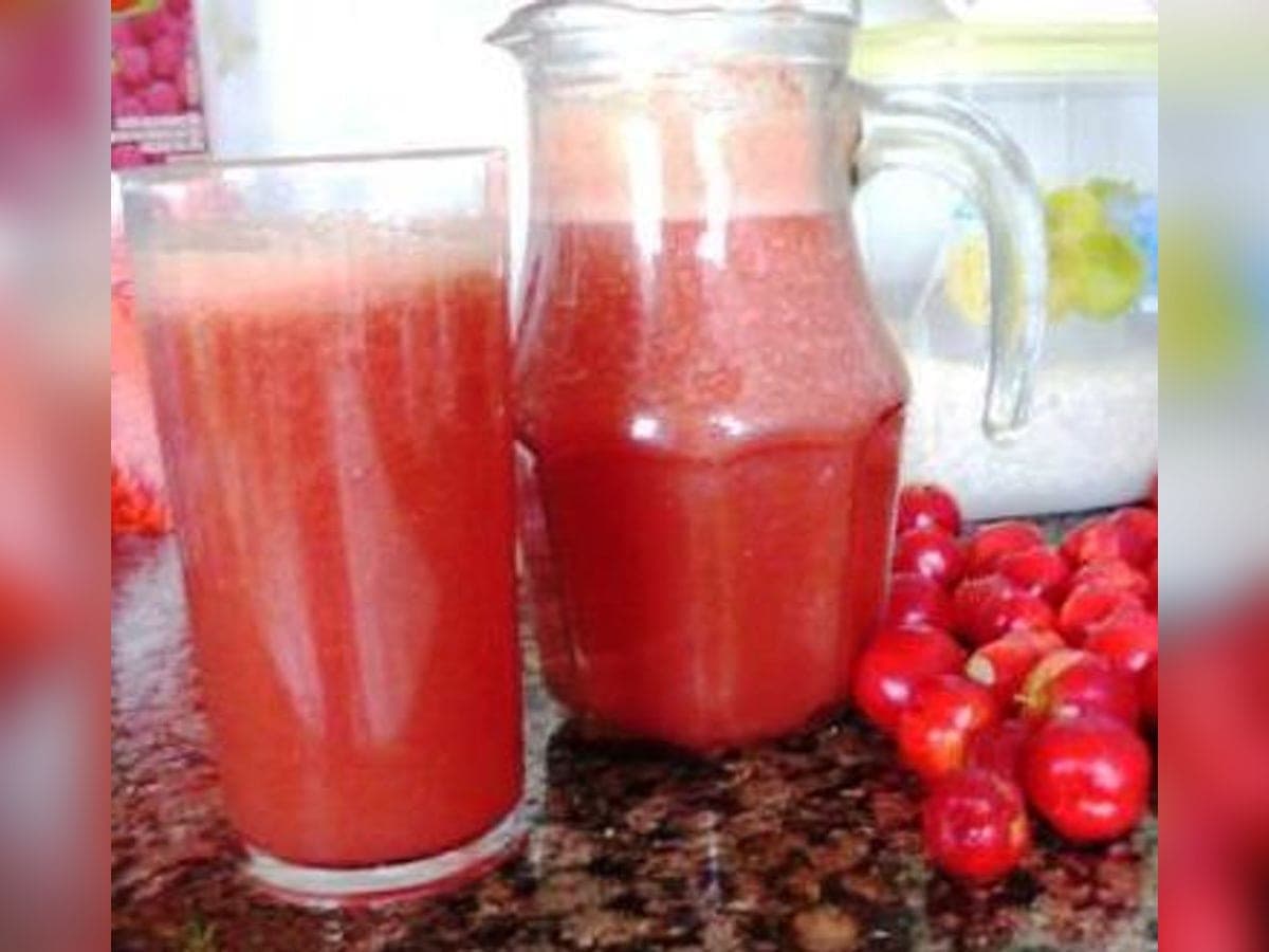 Vaso de jugo de semeruco con hielo, junto a las cerezas de semeruco frescas