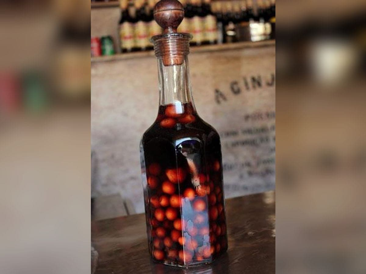 Botella de ron de ponsigué oscuro con los frutos macerados dentro