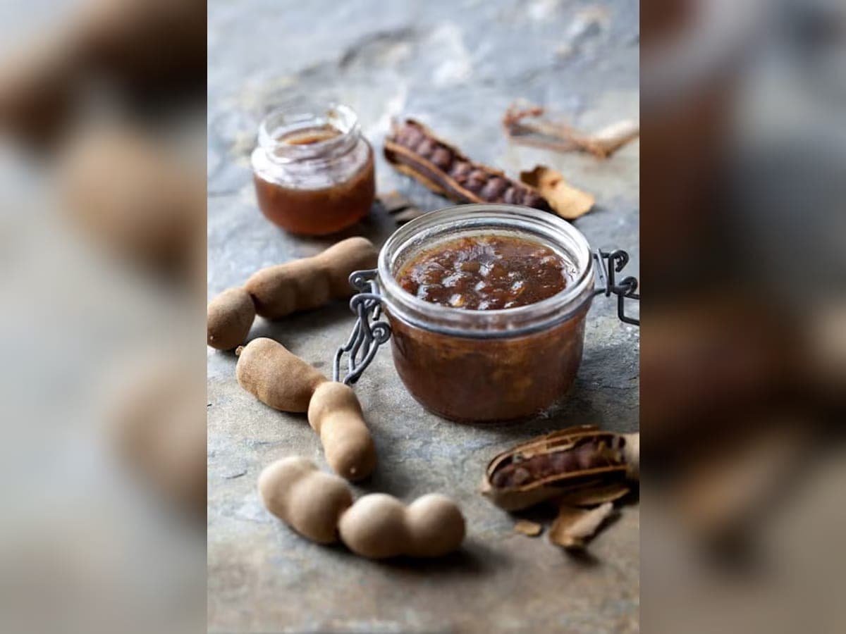 Aderezo de tamarindo emulsionado en un cuenco, junto a hojas de albahaca