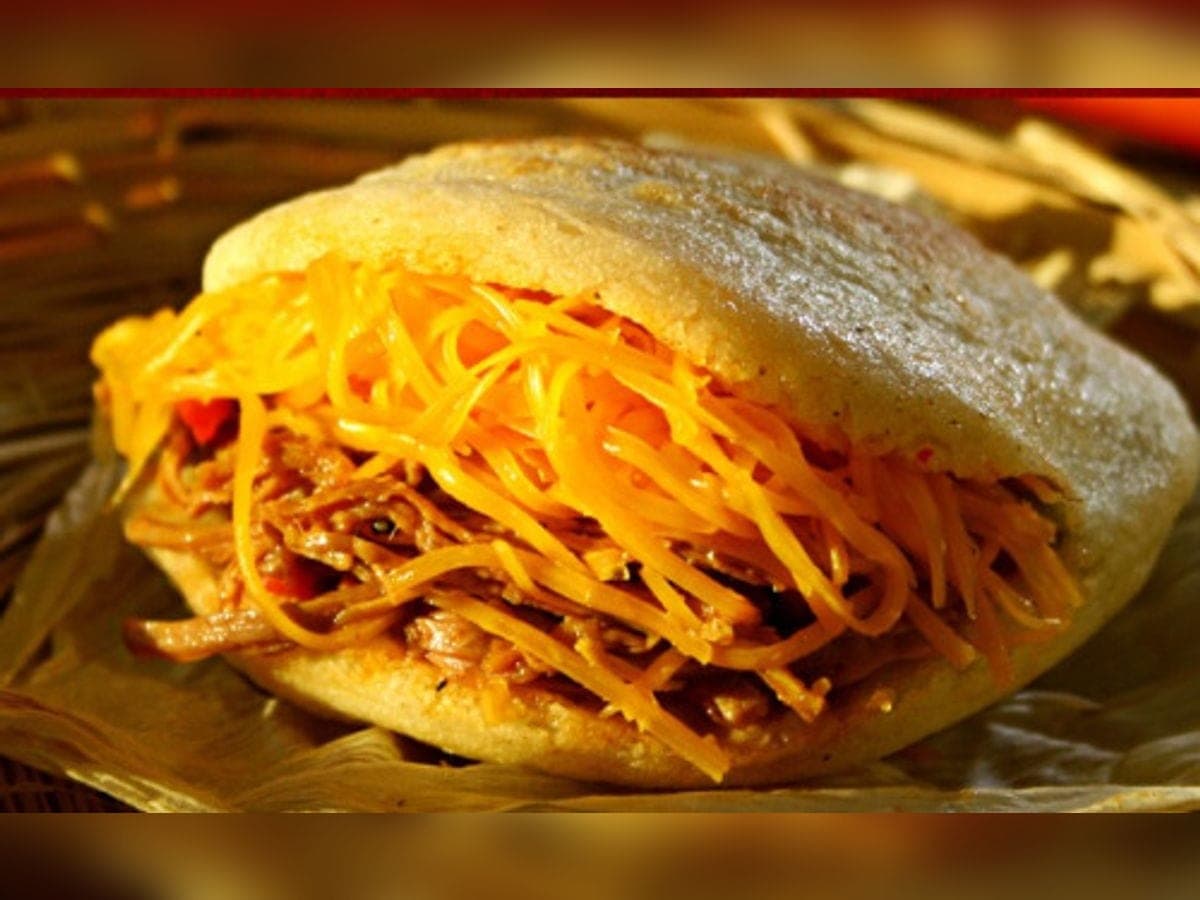 Arepa abierta rellena de carne mechada y queso amarillo rallado