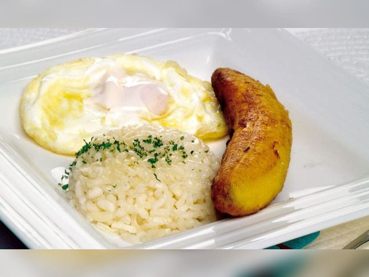 Plato con arroz moldeado, dos huevos fritos encima y tajadas de plátano al lado