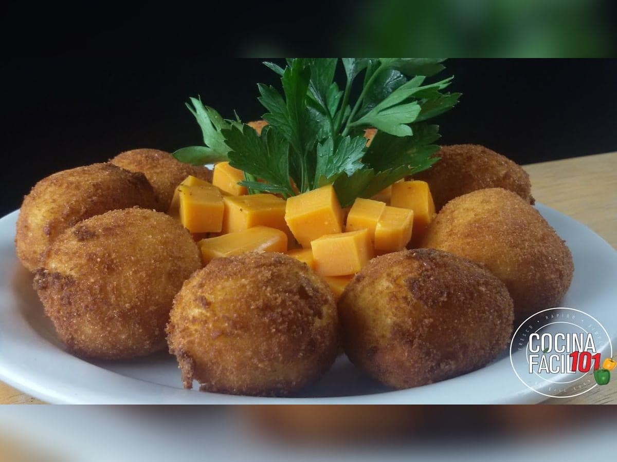 Bollitos de plátano maduro fritos y dorados, uno partido con el relleno de pescado