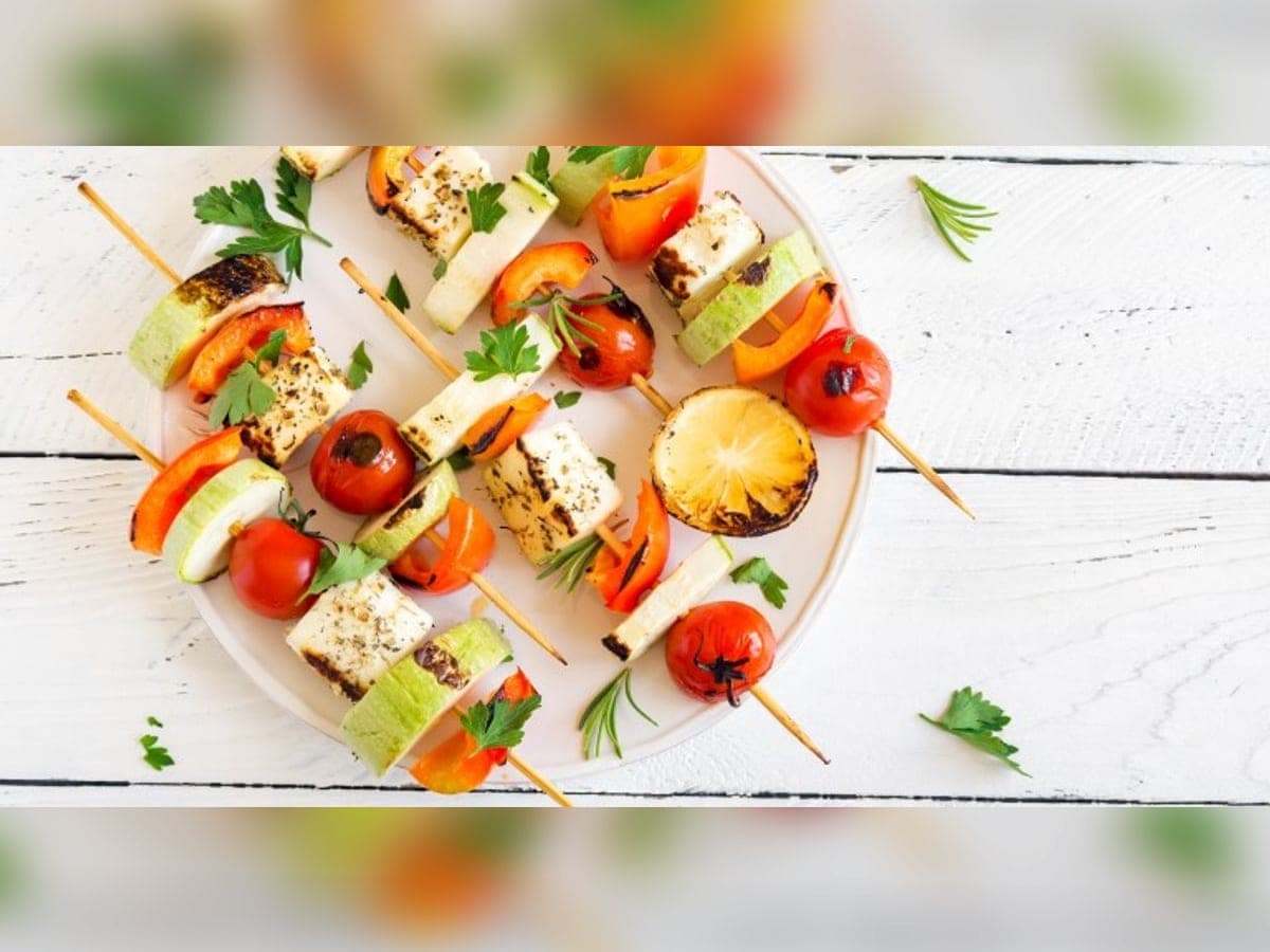 Brochetas de verduras a la parrilla con calabacín, tomate cherry y pimentón, servidas en un plato blanco