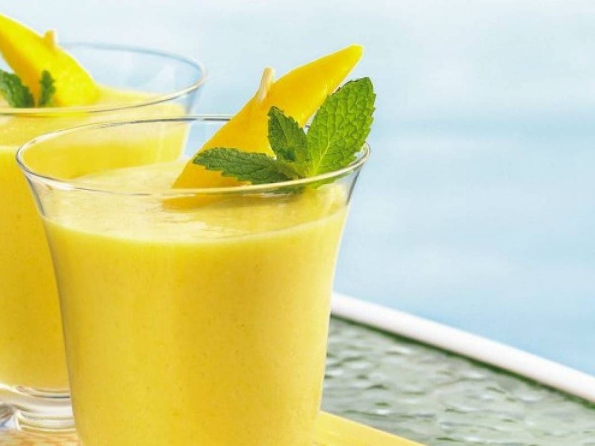 Dos vasos de carato de mango espeso, decorados con trozos de mango y hojas de menta