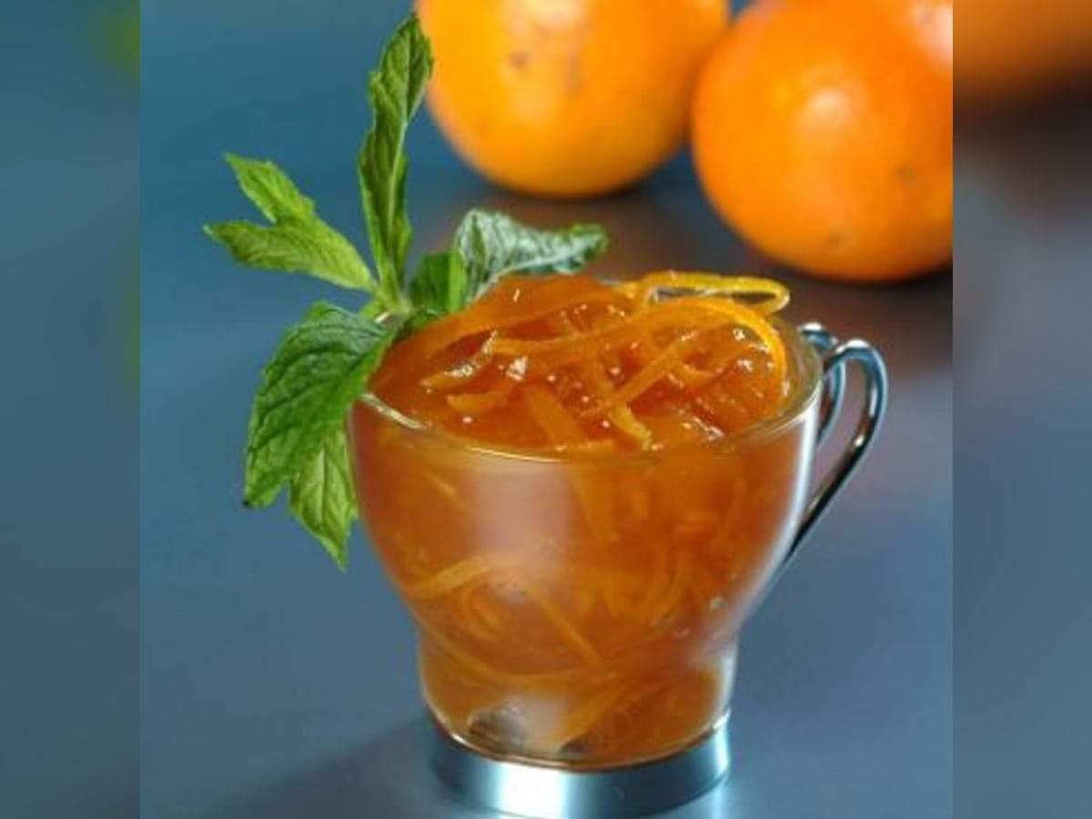 Cascos de naranja confitados en almíbar, servidos en un plato hondo con su jarabe