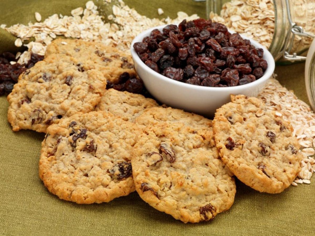 Galletas de avena y pasas doradas apiladas sobre una superficie clara