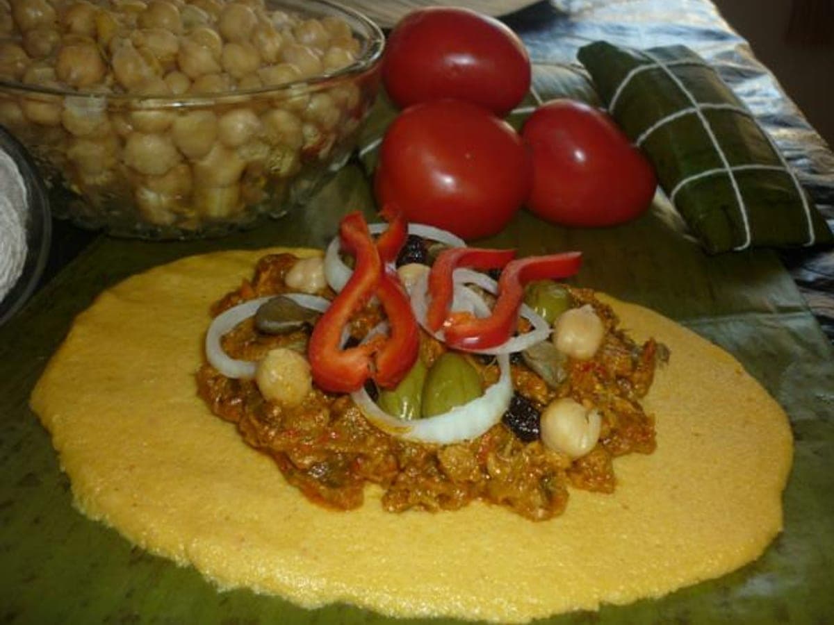 Hallaca andina abierta sobre su hoja de plátano, con el guiso a la vista