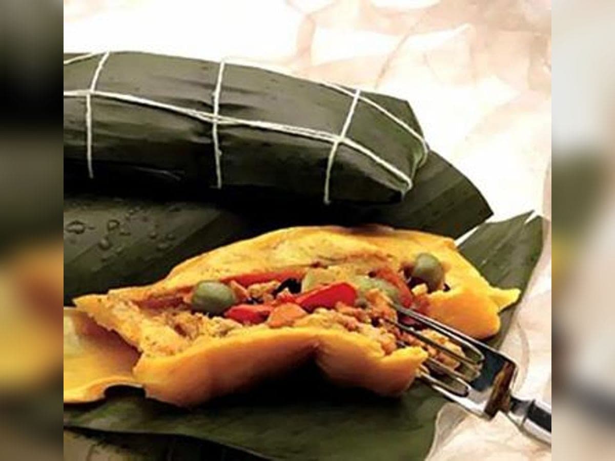 Hallacas amarradas con pabilo y una abierta sobre su hoja de plátano