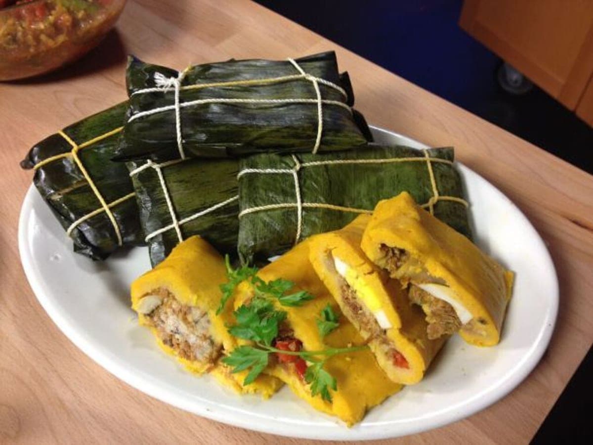 Hallaca vegetariana envuelta en hoja de plátano, abierta y mostrando la masa y el guiso vegetal