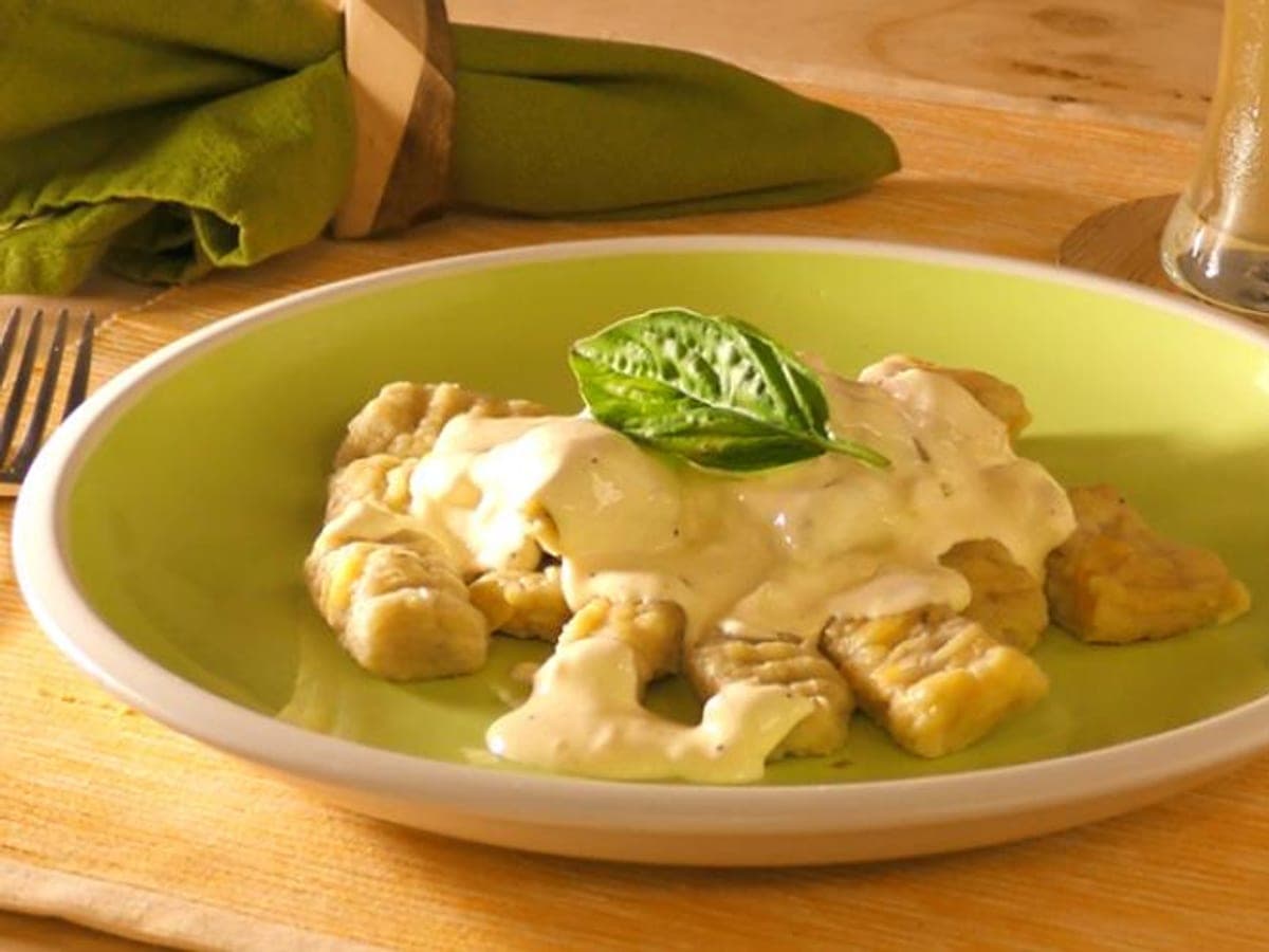 Ñoquis de plátano bañados en salsa de queso en un plato hondo