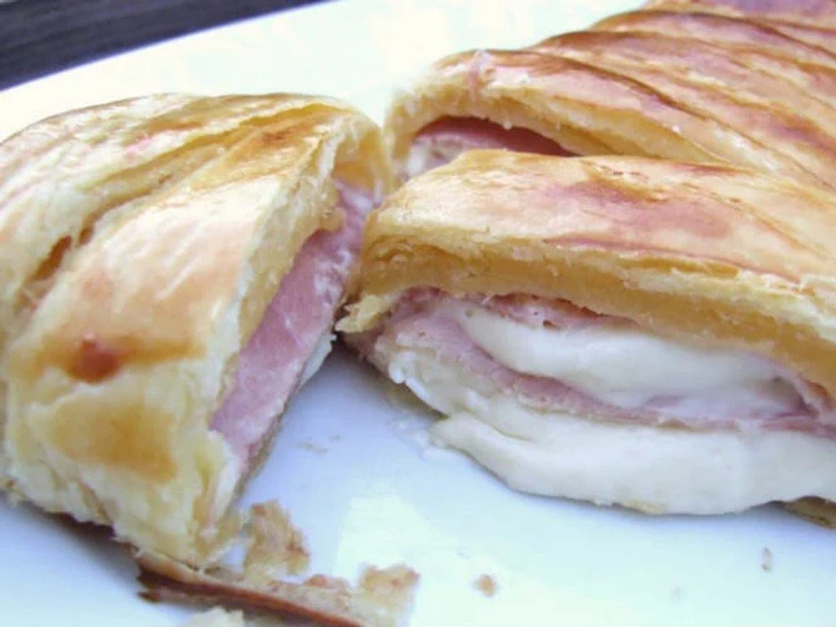 Rollo de hojaldre relleno de jamón y queso crema, dorado y cortado en rebanadas