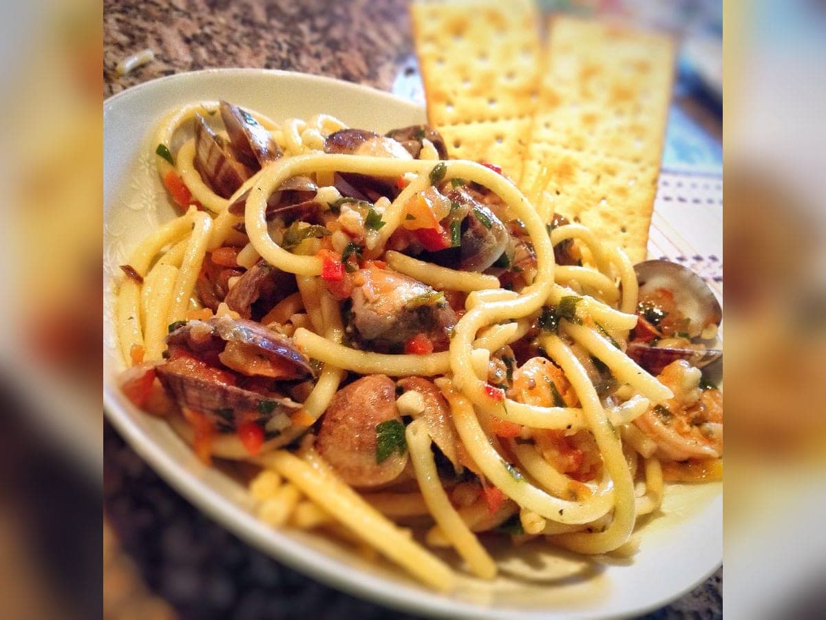 Plato de pasta con salsa roja de guacucos, decorado con conchas