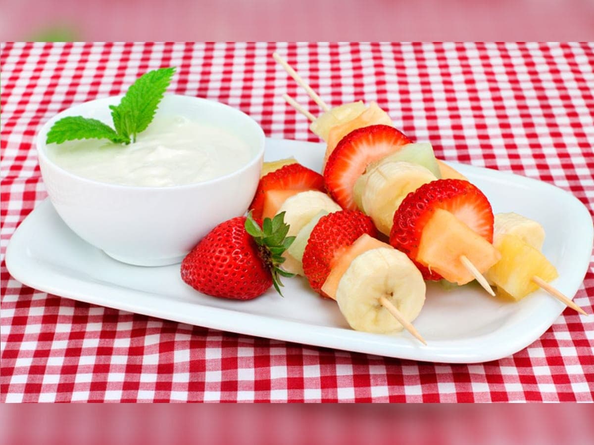 Pinchos de frutas frescas con melón, piña, fresa y cambur, servidos junto a una crema blanca para dip