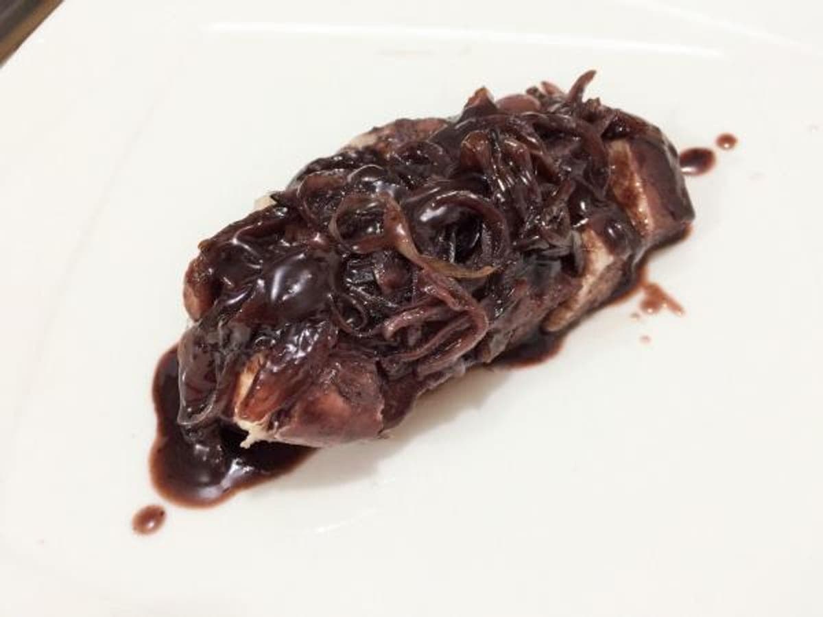 Pechuga de pollo dorada bañada en salsa oscura de vino tinto con cebolla