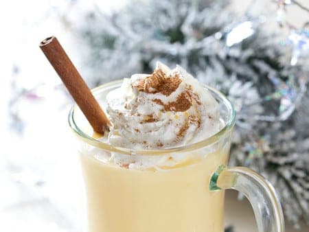 Vaso de ponche andino cremoso adornado con una astilla de canela