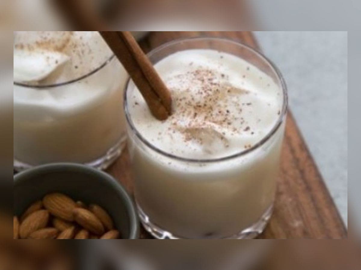 Ponche de crema sin lactosa servido en vasos, espolvoreado con canela y acompañado de almendras