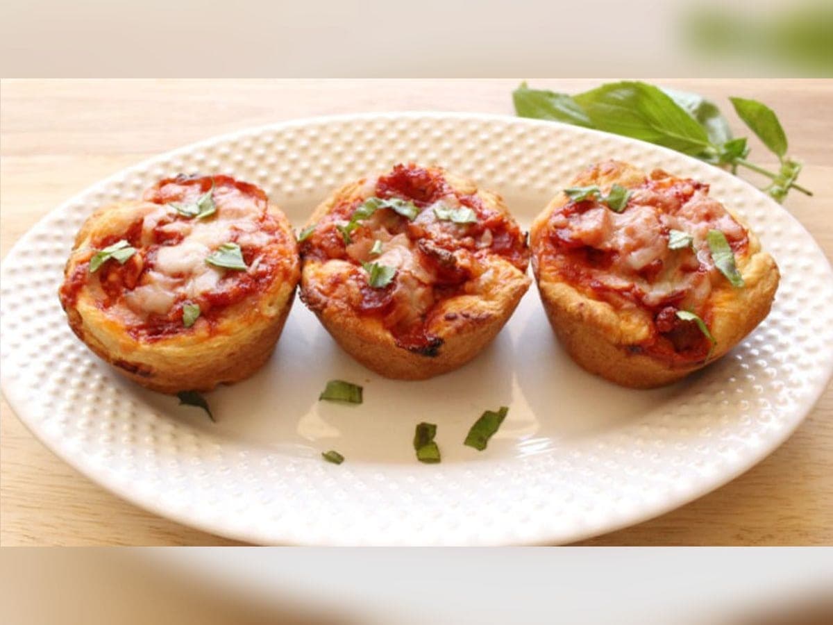 Ponquesitos de pizza recién horneados en su molde de cupcakes, con pepperoni y queso parmesano