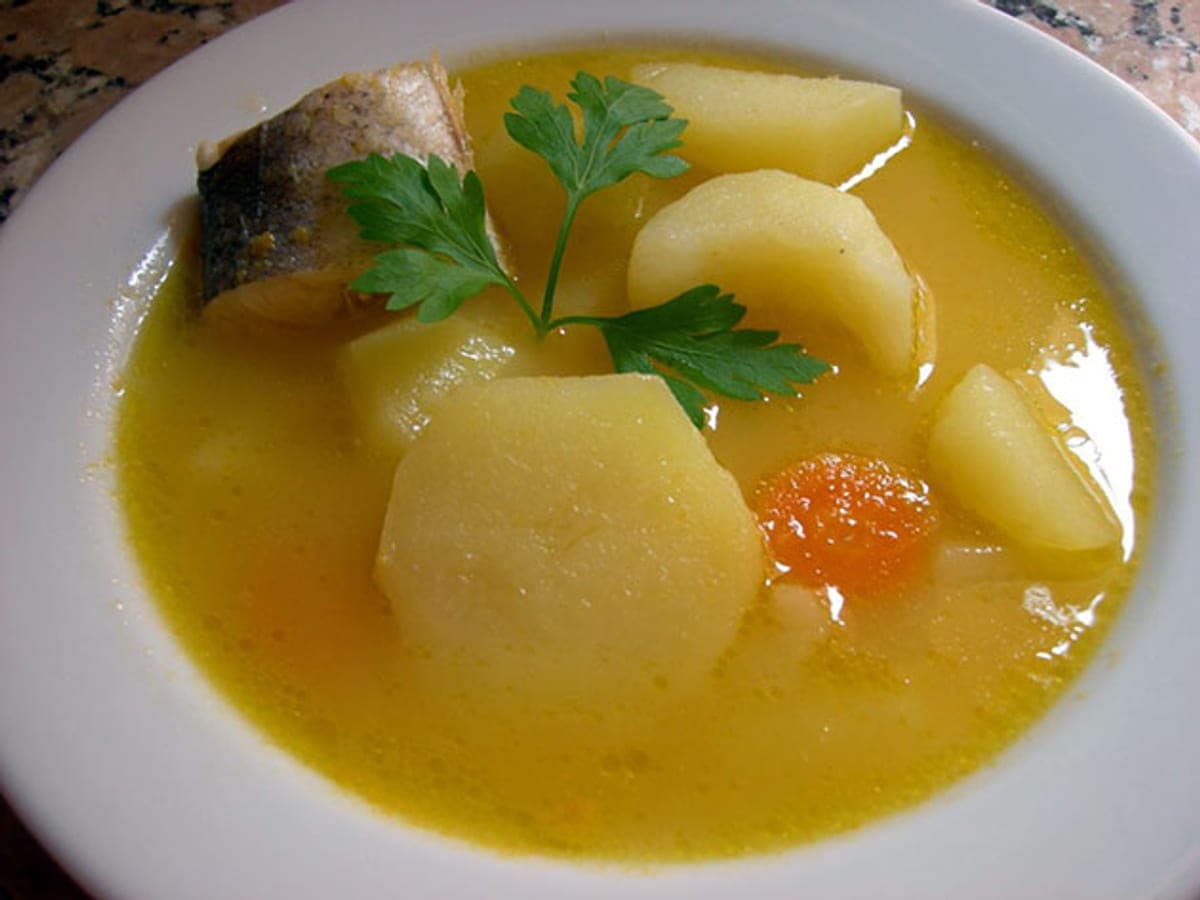 Sancocho de guaraguara servido en plato hondo, con el pescado de río entre las verduras