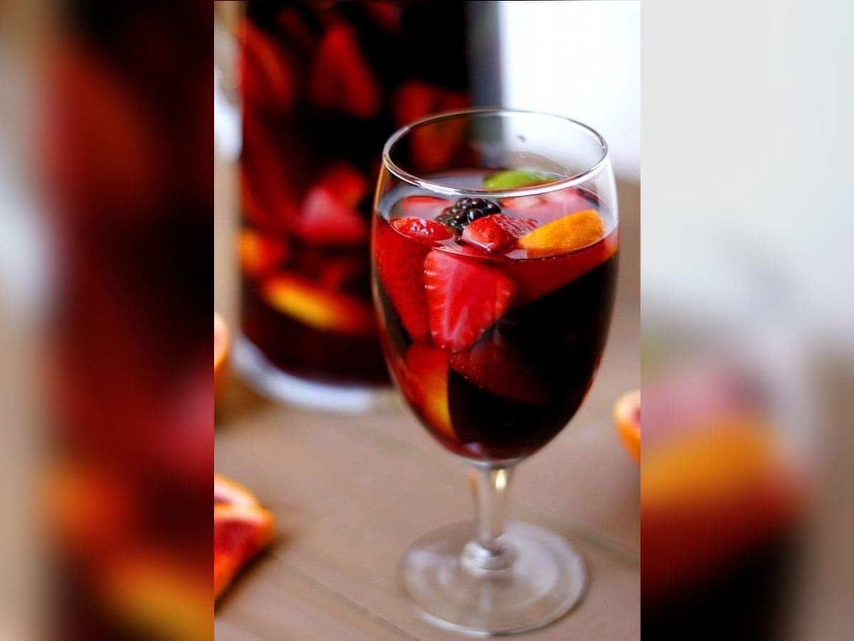 Jarra de sangría andina con rodajas de naranja, fresas y moras