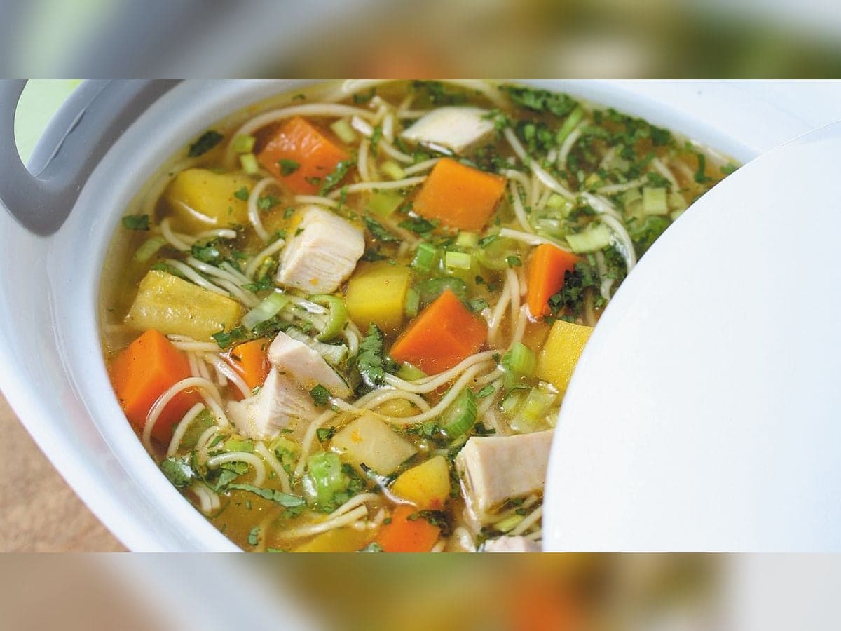 Plato hondo de sopa de pollo con fideos, zanahoria y cilantro picado