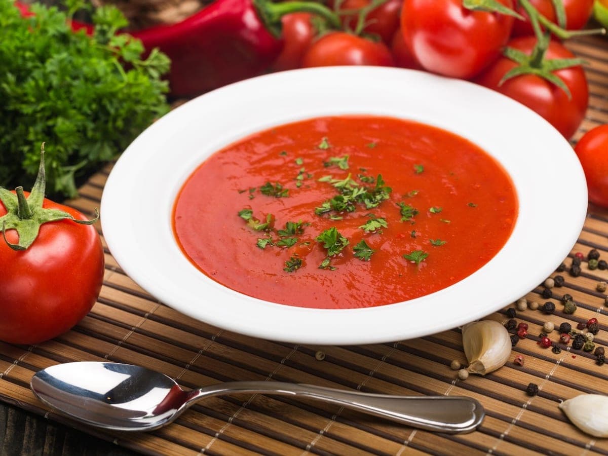Plato hondo de sopa de tomates asados con albahaca picada por encima