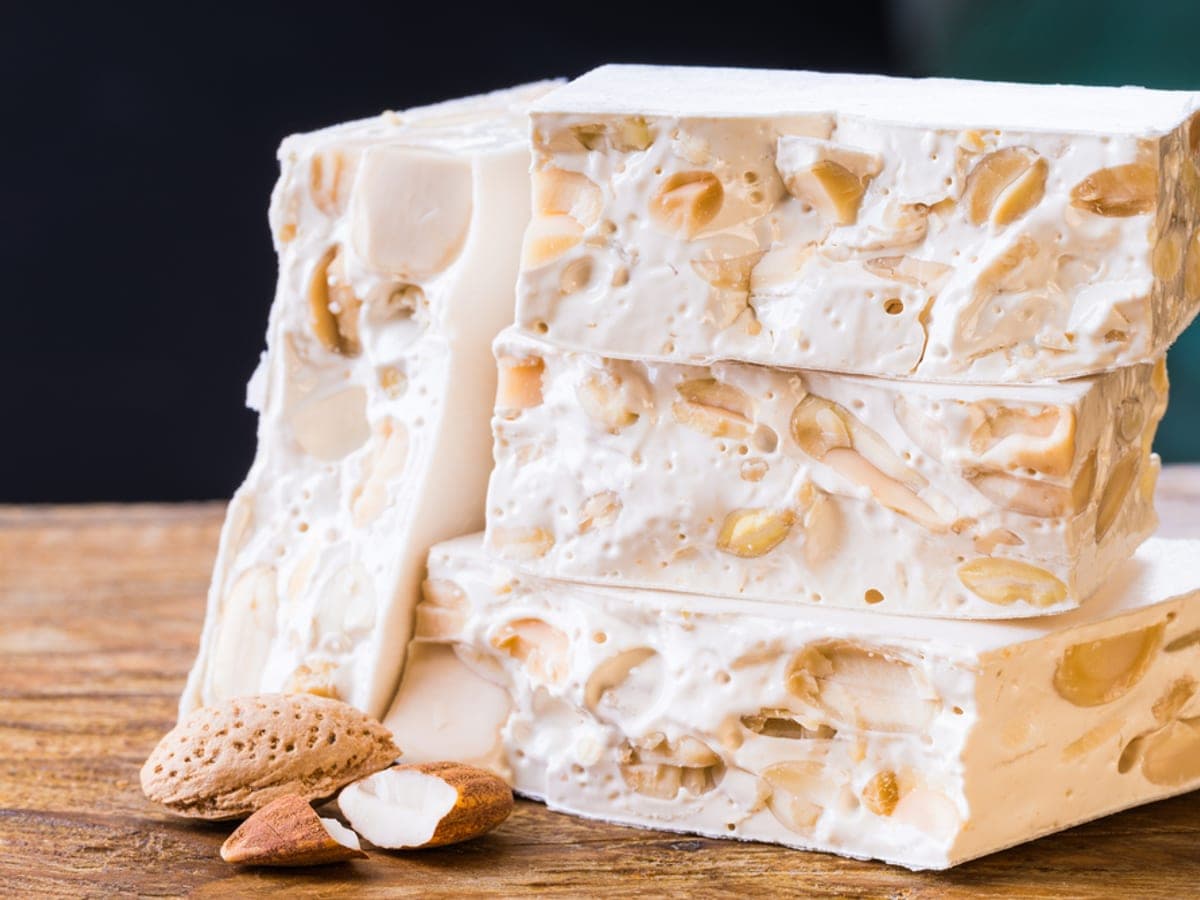 Barra de turrón de almendras cortada en trozos sobre una tabla